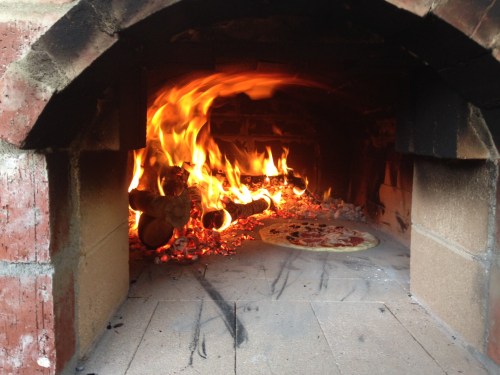 A wonderful shot of the flames leaping toward the pizza